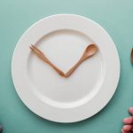 Intermittent fasting image with wooden spoon and fork as a clock hands on white plate, Intermittent fasting concept, ketogenic diet, weight loss, skip meal
